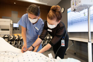 Nurse teaching another nurse how to insert IV needle